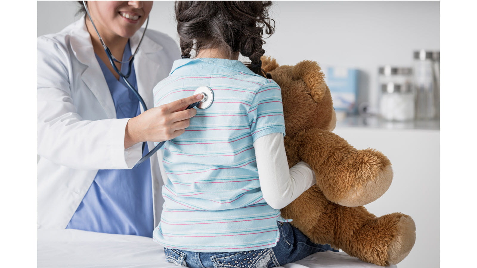 Child holds teddy bear during a medical visit